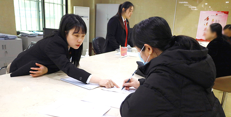 訴訟服務(wù)中心窗口工作人員正在指導(dǎo)前來立案的王女士填寫要素式起訴狀