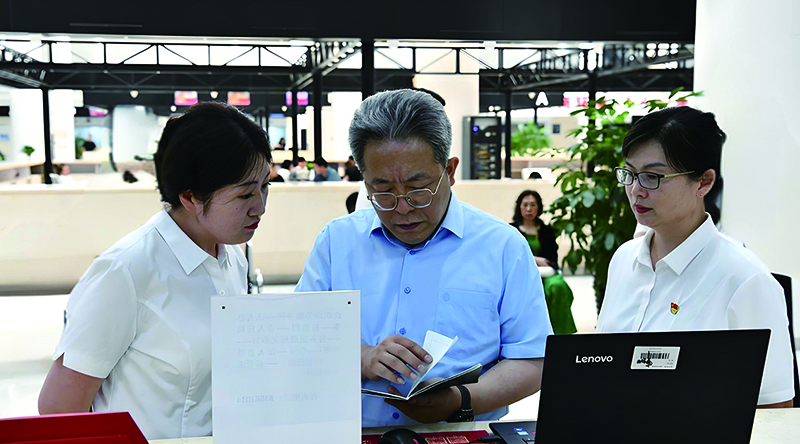 沈陽(yáng)市司法局黨組書記、局長(zhǎng)張勇航（左二）在市政務(wù)服務(wù)中心向窗口工作人員了解審批流程