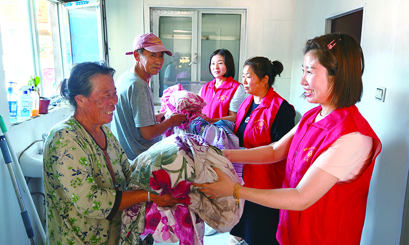 高齡老人將需要清洗的衣物送到愛(ài)心洗衣房