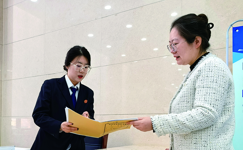 訴服中心的涉企案件綠色通道窗口，法官助理張嘉鑫正耐心指導(dǎo)當(dāng)事人填寫訴答文書