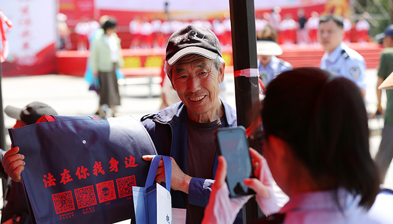 頭題圖，法治文藝節(jié)目展演活動(dòng)現(xiàn)場，司法局工作人員發(fā)放原創(chuàng)普法購物袋。